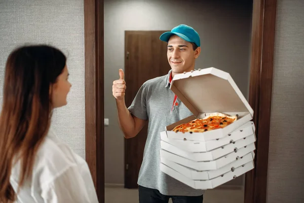 Cheerful pizza delivery boy shows thumbs up symbol to female customer, fast...