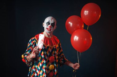Çirkin lanet palyaço et cleaver ile hava balonları, korku tutar. Makyaj karnaval kılık, manyağı adamla