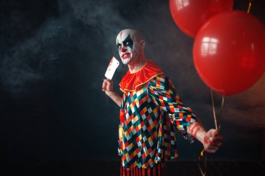 Çirkin lanet palyaço et cleaver ile hava balonu, korku tutar. Makyaj karnaval kılık, deli manyak adam