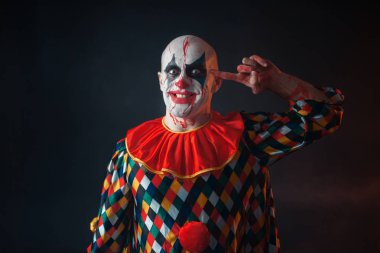Deli kanlı palyaço portresi parmak onun Tapınağı, yüzü kan içinde twirls. Makyaj içinde halloween kılık, manyağı adamla 