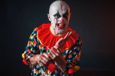 Deli kanlı palyaço insan eli, dişlerini parmak tutar. Makyaj içinde halloween kılık, manyağı adamla 