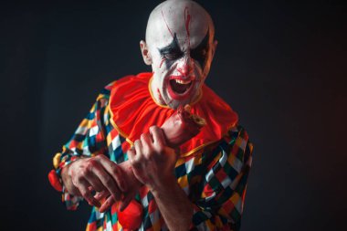 Deli kanlı palyaço insan eli, dişlerini parmak tutar. Makyaj içinde halloween kılık, manyağı adamla