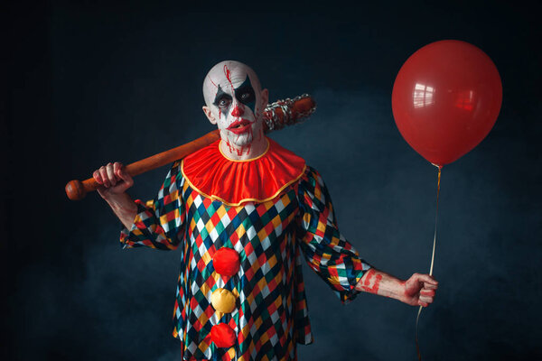 Ugly bloody clown with baseball bat and air balloon, horror. Man with makeup in carnival costume, crazy maniac