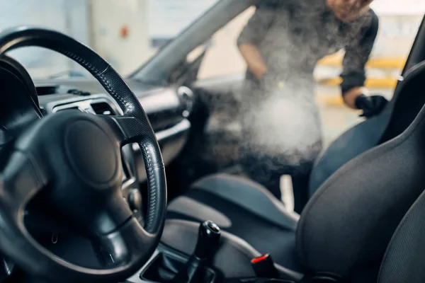 Professional dry cleaning of car salon with steam cleaner. Carwash service, vehicle salon hygiene, male worker removes dirt and dust — Stock Image Professional Dry Cleaning Car Salon Steam Cleaner Carwash Service Vehicle Royalty Free Stock Images
