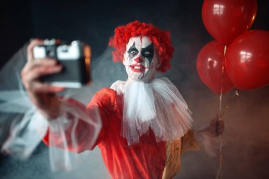 Korkunç lanet palyaço deli gözler ile selfie yapar. Makyaj karnaval kılık, deli manyak adam