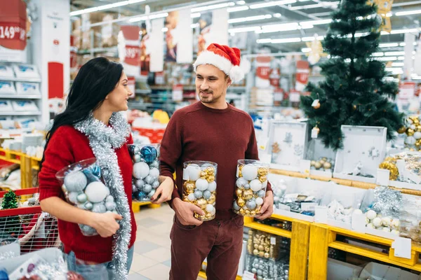 年轻夫妇与盒子里的圣诞球在商店 家庭传统 12月假日物品和装饰品的购物 — 图库照片