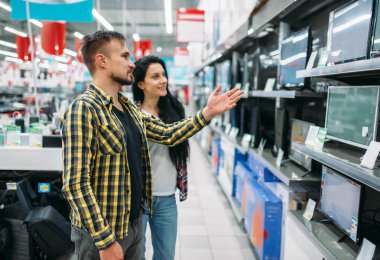 Genç çift monitör süpermarkette satın alma. Kadın ve erkek müşteriler aile alışveriş üzerinde. Erkek ve kadın ev için mal satın alma