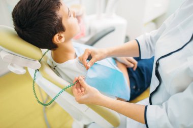 Çocuk diş sandalye, çocuk diş hekimliği. Doktor küçük bir hasta diş inceliyor