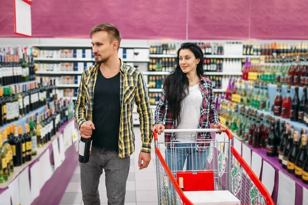 Young couple in supermarket, holiday shopping. Male and female customers buying alcohol. Man and woman purchasing beverages