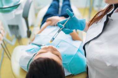 Enjeksiyon anestezi, çocuk diş sandalye, çocuk diş hekimliği, çocuklar stomatology. Kadın dişçi bir atış yapar
