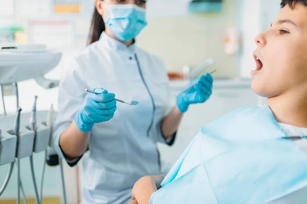 歯科用椅子 専門の小児歯科 子供の口腔病学 マスクと手袋を背景に女性歯科医でほとんどの患者 — ストック写真