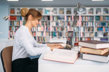Kız öğrenci, Üniversite Kütüphanesi içinde belgili tanımlık laptop. Okuma odası, bilgi deposu olarak genç kadın