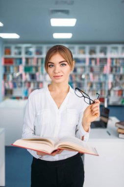 Güzel kız öğrencinin Üniversite Kütüphanesi açılan kitap ile. Okuma odası, bilgi deposu olarak genç kadın