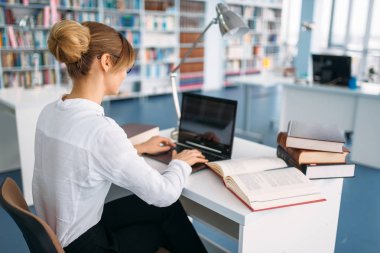 Kız öğrenci, Üniversite Kütüphanesi içinde belgili tanımlık laptop. Okuma odası, bilgi deposu olarak genç kadın
