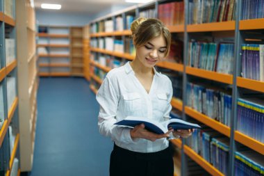 Kız öğrencinin Üniversitesi Kütüphane rafları arasında kitap ile. Okuma odası, bilgi deposu olarak genç kadın
