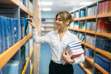 Çok kadın insan Üniversitesi Kütüphane rafları arasında kitap yığını. Okuma odası, bilgi deposu olarak genç kadın