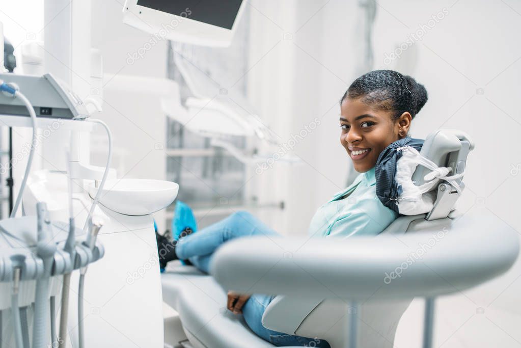 Smiling female patient on chair, visit in dental clinic. Woman in dentistry cabinet, stomatology, tooth care