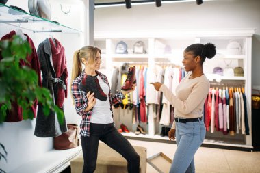 Alışveriş iki kadın elbise ve ayakkabı, satın. Shopaholics giyim mağazası, tüketim yaşam tarzı, moda