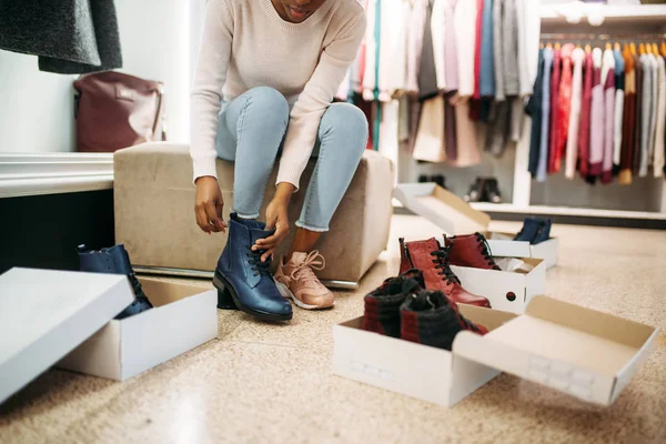 Black female person trying on shoes, shopping. Shopaholic in clothing store, consumerism lifestyle, fashion