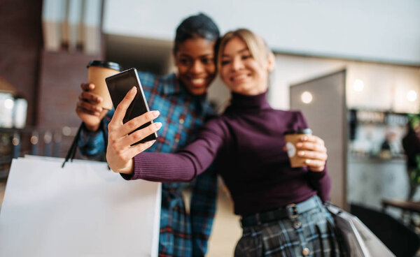 Two girlfriends makes selfie in shop, shopping. Shopaholics in clothing store, consumerism lifestyle, fashion