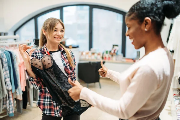 İki kadın seçme samimi giyim, alışveriş. Shopaholics Giyim Mağazası, tüketim yaşam tarzı, moda, iç çamaşırı bölümünde kadın alışveriş
