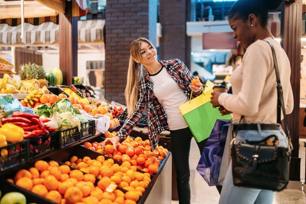 两个年轻的有魅力的女人在购物后买水果 食品店里的购物狂 消费主义的生活方式 带着包的女性购物者 — 图库照片