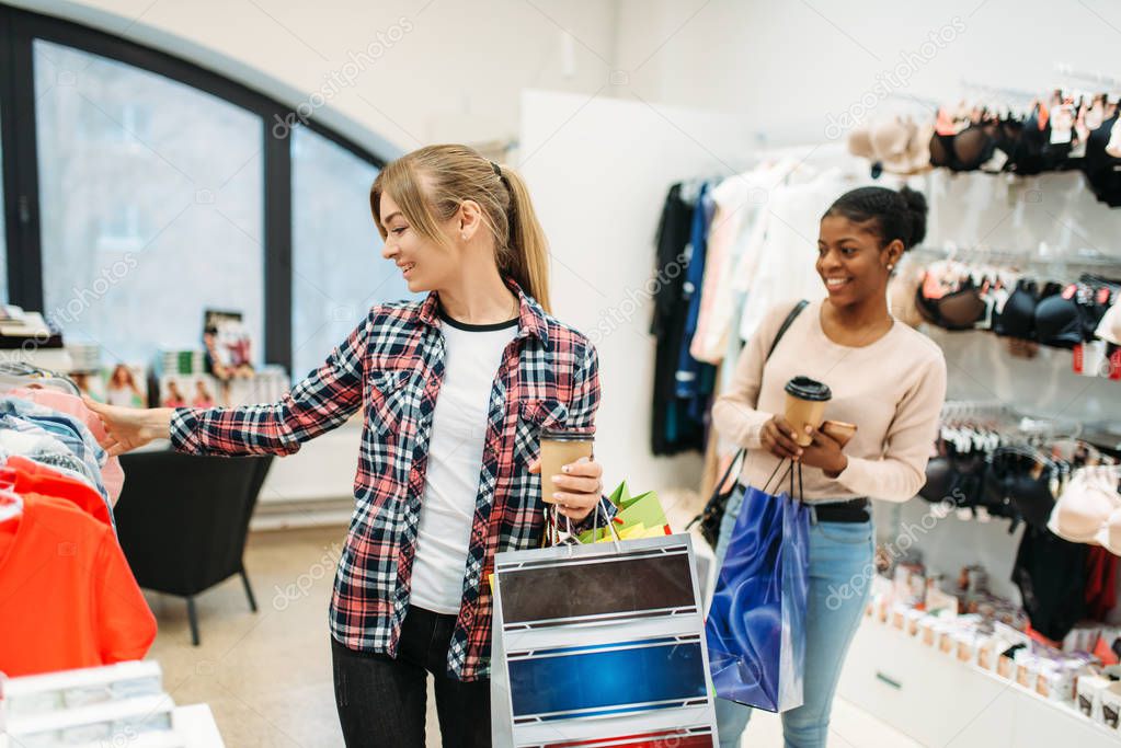 two young attractive women shopping, ladies lingerie. Shopaholics in clothing store, consumerism lifestyle, fashion, female shoppers with bags