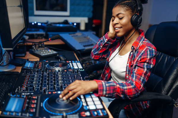 Female sound operator working at the remote control panel in audio recording studio.  Musician at the mixer, professional music mixing