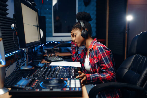 Female sound operator working at the remote control panel in audio recording studio. Musician at the mixer, professional music mixing