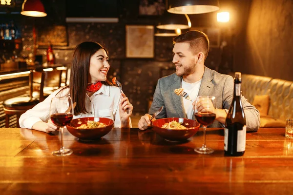 Couple at wooden bar counter, romantic dinner with red wine. Lovers leisures in pub, husband and wife relaxing together in nightclub