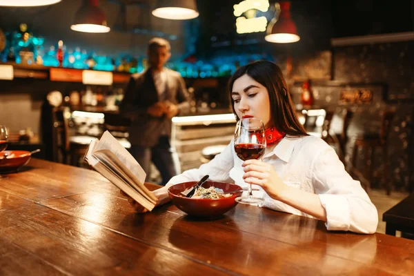 Νεαρή Γυναίκα Πίνει Κόκκινο Κρασί Και Διαβάζοντας Ένα Βιβλίο Στον — Φωτογραφία Αρχείου