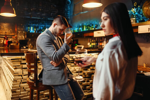 Sad man and woman in a bar, husband and wife relaxing together in nightclub