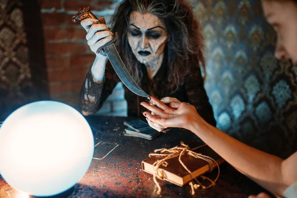 ナイフで怖い魔女は 水晶玉を精神的な降霊会に若い人々 に魔法の呪文を読み取ります 女性の占い霊を呼び出す — ストック写真
