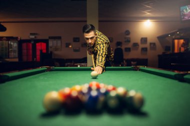 Tablo renkli topları ile nişan işaret erkek bilardo oyuncusu. Adam Amerikan pool oyunu spor barda oynuyor.