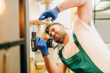 Tamirci üniformalı tornavida tutan el ulağı. Profesyonel çalışan çevresinde ev, ev tamir servisi onarım yapar