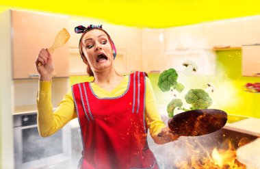 Brokoli yanıyor, mutfak iç arka plan üzerinde yemek önlük çılgın ev kadını. Komik kadın kişi ile bir tavada, işler plana göre gidiyor değil