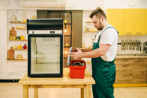 Worker with toolbox repair refrigerator at home. Repairing of fridge occupation, professional technical service