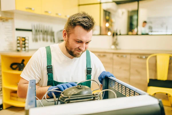 İşçi üniformalı buzdolabı kompresör evde onarır. Buzdolabı işgali sonrasında, profesyonel hizmet onarma