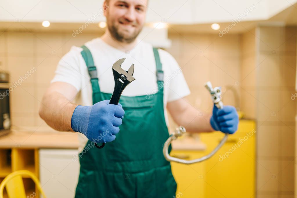 Plumber in uniform holds wrench, handyman. Professional worker makes repairs around the house, home repairing service