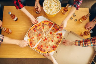 Masadan pizza dilimleri alan arkadaşların elleri, üst görünüm, ev partisi. İyi arkadaşlık, bir grup insan birlikte vakit doldu. Şirket olayı kutluyor