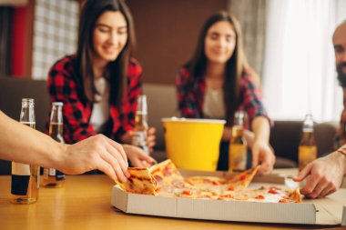Gülümseyen arkadaşlar ev partisinde pizza ile bira içer. İyi dostluk, grup insanlar birlikte vakit geçiriyor. Neşeli şirket olay kutlamak