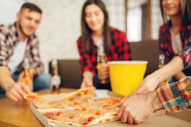 Gülümseyen arkadaşlar ev partisinde pizza ile bira içer. İyi dostluk, grup insanlar birlikte vakit geçiriyor. Neşeli şirket eğlenmek