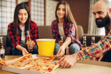 Gülümseyen arkadaşlar ev partisinde pizza ile bira içer. İyi dostluk, grup insanlar birlikte vakit geçiriyor. Neşeli şirket olay kutlamak