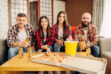 Gülümseyen arkadaşlar ev partisinde pizza ile bira içer. İyi dostluk, grup insanlar birlikte vakit geçiriyor. Neşeli şirket eğlenmek