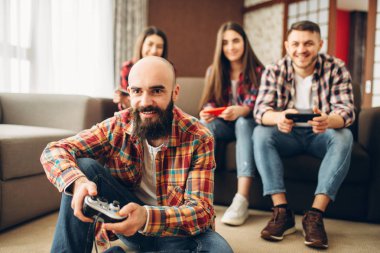 Arkadaşlar oyun çubukları ile gülümseyen tv konsol evde çalış. Grup oyun gamepads video oyunu, kadın ve erkek oyuncularla joypad ile