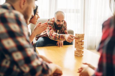 Arkadaşlar evde jenga oynar, adam kuleden ahşap blok çeker. Komik şirket için yüksek konsantrasyon, eğlence gerektiren Masa oyunu