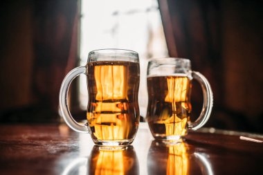 İki bira bardağı ahşap bar counter, makro görünümü, kimse. Octoberfest sembolü. Gözlük ile zemin üzerine güneş ışığı ile'pub, portre, pencere tabloda altın içecek