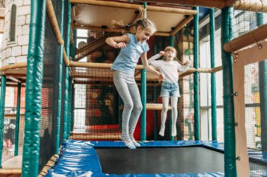 İki komik kız trambolin üzerinde atlama, Çocuk oyun merkezi. Heyecanlı Childs oyun alanı kapalı eğlenmek. Eğlence merkezinde oynayan çocuklar
