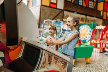 İki küçük kız video oyunu makinede, çocuk eğlence merkezi çalış. Heyecanlı Childs'ın kapalı oyun alanında eğleniyor. Motosiklet, eğlence merkezi oynayan çocuklar