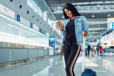 Bavul ve telefon ile siyah kadın turist uluslararası havaalanında kalkış bekliyor. Hava terminalinde bagaj ile Yolcu, mutlu yolculuk seksi bayan, mutlu kadın yaz seyahat